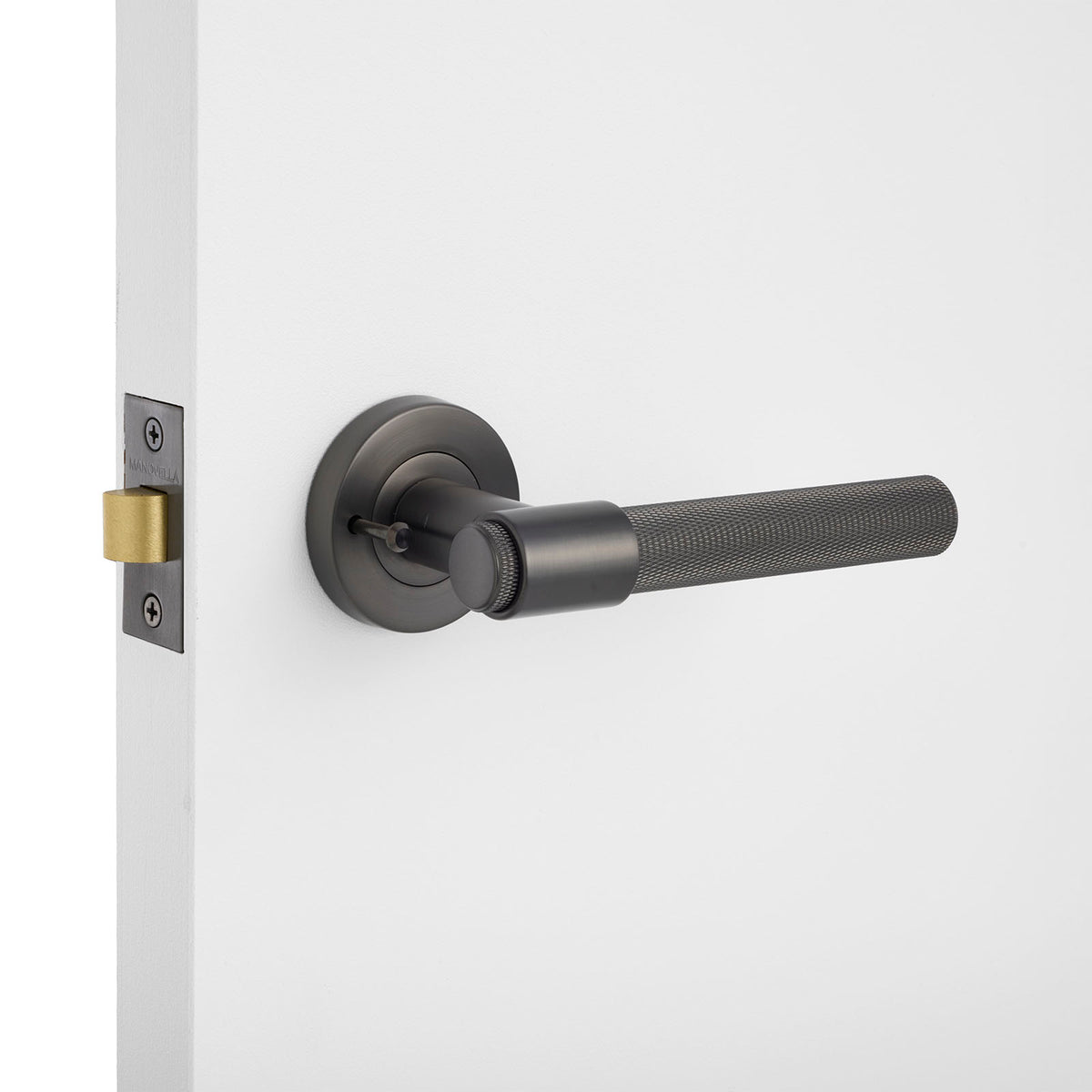 Gunmetal knurled privacydoor handle on a white door with a gold latch.